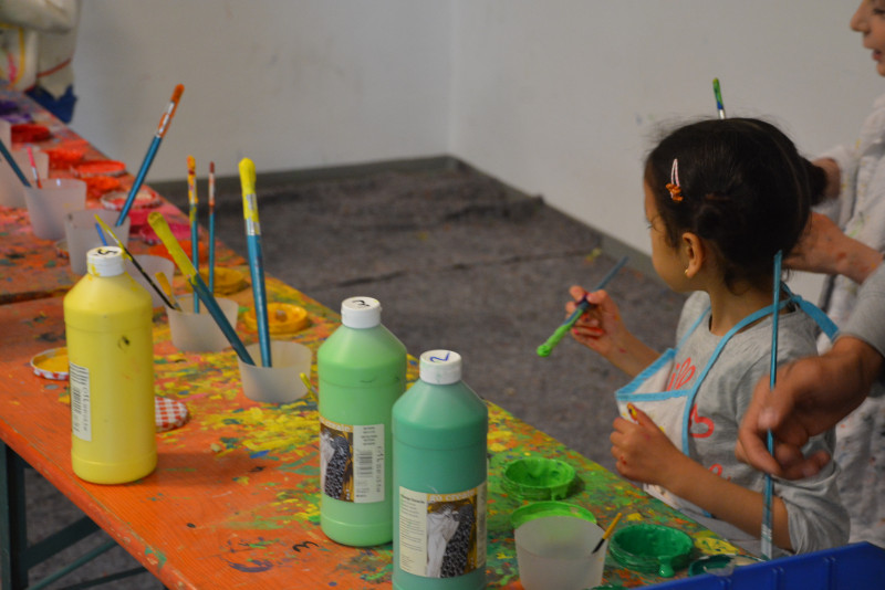 Kinder an Werktisch mit Farbtuben und Pinseln