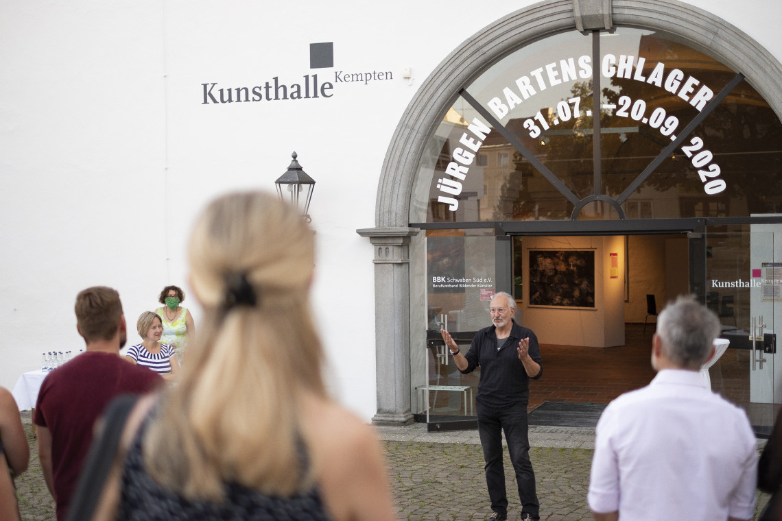 Künstler Jürgen Bartenschlager spricht vor dem Eingang zur Kunsthalle Kempten zu Menschengruppe