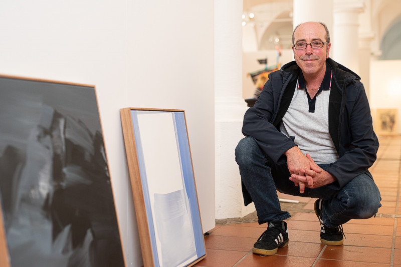 Künstler Stefan Winkler neben seinen beiden prämierten Bildern
